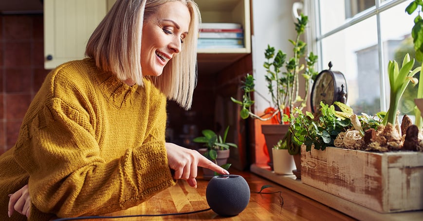 woman interacting with her smart speaker at home